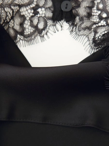 Detailaufnahme aus schwarzer Spitze und Satin mit Knopfverschluss am Neckholder-Top