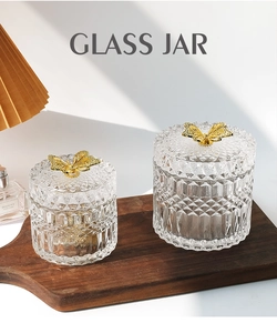 Close-up of glass storage jars with relief texture and golden butterfly lids on a tray