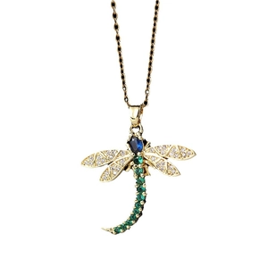 Gold dragonfly necklace featuring blue gemstone head and green crystal wings on white background