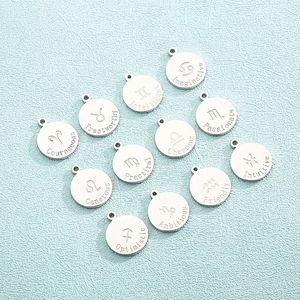 Flat lay of 12 silver zodiac pendants with engraved character traits on blue background