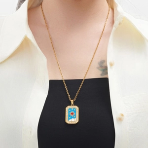 Golden necklace with a rectangular celestial pendant and white zircons worn on a model