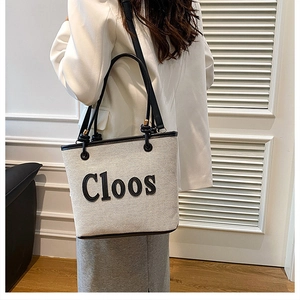 Fashionable off-white canvas tote bag with black trim and Cloos print on model
