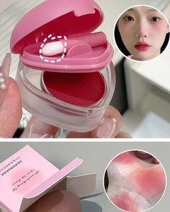 Macro detail of matte red lip and cheek mud with heart-shaped case and applicator brush