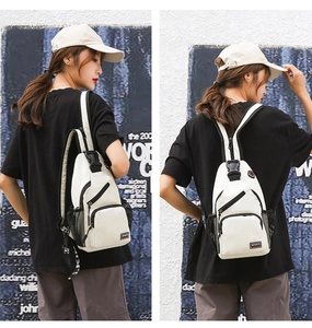 Detail of white nylon chest bag with black trim and sports patch worn by model