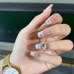 Detail of long coffin press-on nails with nude French tip, rhinestones and heart crystals