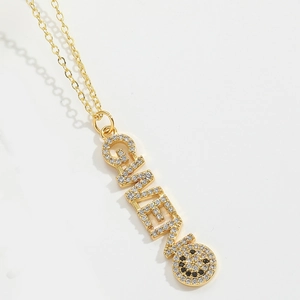 Detailed close-up of golden GINEVA letter pendant necklace with a smiling face charm