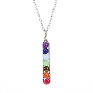 Macro view of handmade wire wrapped chakra pendant with seven colorful gemstone beads