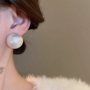 Gros plan d'une élégante grande boucle d'oreille ronde en perle blanche sur le mannequin