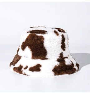 Close-up of soft plush cow print bucket hat with realistic brown and white faux fur texture