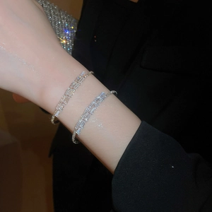 Close-up of elegant silver bracelets with square cubic zirconia on a model with black suit