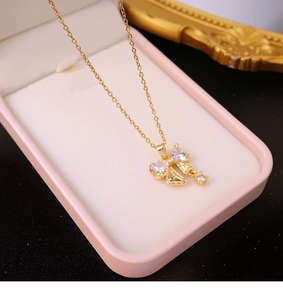Gros plan détaillé d'un collier pendentif nœud doré avec zircons dans un écrin rose