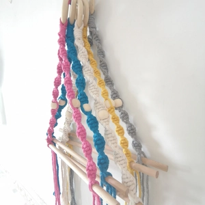 Detail of colorful macrame toilet paper holder with handwoven cotton ropes and wooden rods