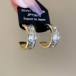 Macro shot of 925 silver C-shape earrings with two-tone gold plating and silver glitter