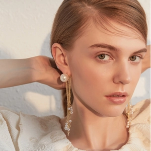 Elegant gold long tassel earrings with pearls on model in warm studio lighting