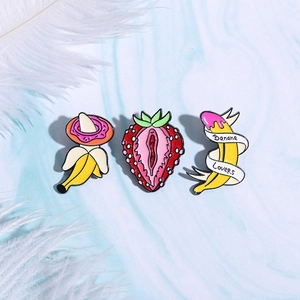 Cartoon fruit enamel pins featuring banana and strawberry designs on marble background