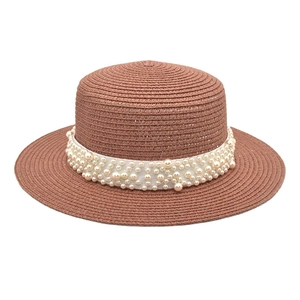 Détail d'un chapeau de paille marron avec perles élégantes sur ruban blanc décoratif