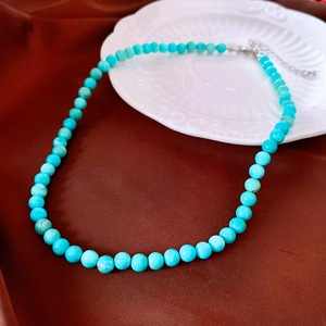 Détail du collier en perles turquoise sur porcelaine blanche avec fermoir argenté