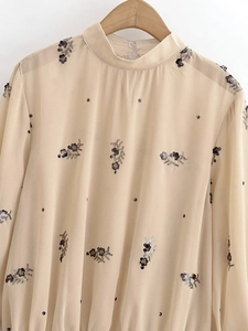 Détail du haut en mousseline beige avec broderies de fleurs en paillettes noires et argent