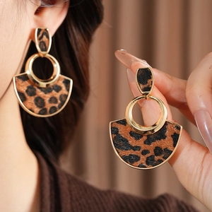 Detailed close-up of leopard print fan-shaped earrings with golden geometric metal frame