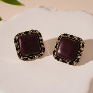 Detail shot of vintage square earrings with dark red stones on white pedestal