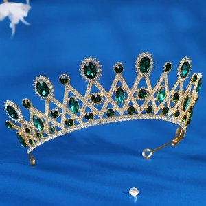 Detail of a gold baroque bridal crown with green crystals on dark blue silk fabric
