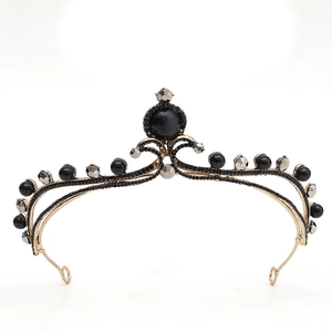 Détail de la couronne baroque avec perles noires et monture en métal doré sur fond blanc