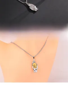 Macro view of two-tone religious pendant with silver praying hands and gold buddha head detail