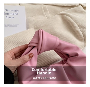 Close-up of a pink ruched cloud bag featuring a knotted handle and soft matte leather texture