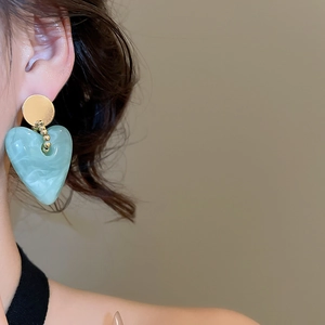 Detail of turquoise heart drop earrings with gold beads on model for retro style