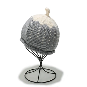 Détail du bonnet tricoté pour bébé gris et blanc avec motifs de cœur et bordure roulée