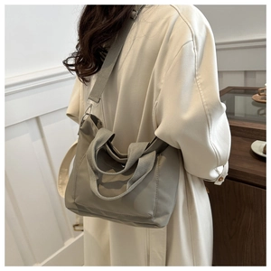 Primer plano de un bolso tote de nailon gris con correa ancha ajustable para mujer