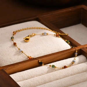 Minimalist gold anklet with colorful natural stone beads on a wooden jewelry display