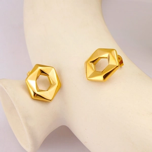 Macro detail of geometric hexagonal gold earrings on a minimalist display stand