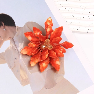 Detail of elegant orange acrylic flower brooch with tassels on a fashion magazine