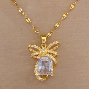 Macro shot of luxury gold bow pendant featuring square central gemstone and pavé diamonds