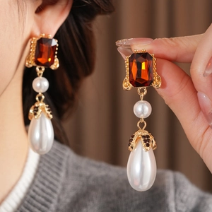 Detailed view of vintage amber crystal earrings with waterdrop pearls and gold accents