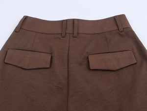 Macro view of brown pleated trousers showing back waist belt loops and flap pockets