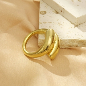 Artistic detail of a thick golden wrap ring on silk fabric and textured stone background