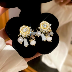Detailed macro of vintage style gold earrings with pearl tassels and shimmering crystals