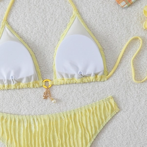 Detail of yellow bikini top featuring a golden ring with starfish and pearl charms