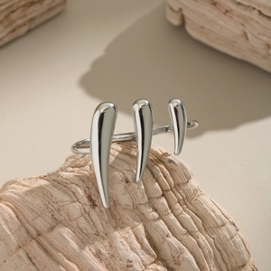 Bague griffe en acier inoxydable argenté poli sur une surface en roche naturelle