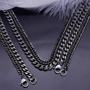 Close-up of thick stainless steel Cuban link necklace with lobster clasp on dark surface