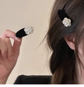 Close-up of elegant black velvet camellia hair clips with white pearls for women