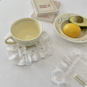 Detail of white cotton linen coasters with blue heart pattern and ruffled edges