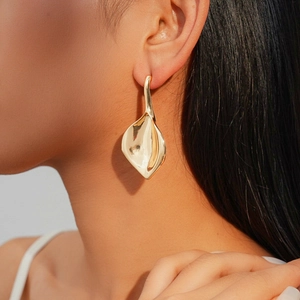 Gros plan de boucles d'oreilles feuille losange dorées polies au design organique moderne