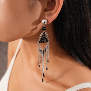 Close-up of long silver chain tassel earrings with black beads on a female model