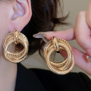 Detailed view of layered gold circular earrings featuring a mix of matte and polished finishes