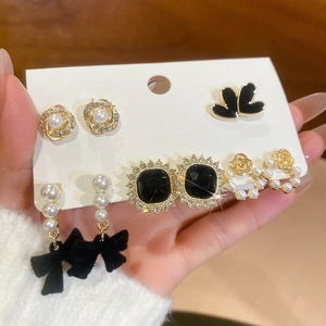 Detail view of pearl and diamond stud earring set with black velvet bow charms