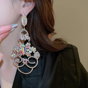 Détail des boucles d'oreilles pampilles en strass avec texture florale scintillante