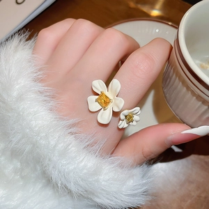 Detail of floral ring with white petals and yellow zircon on model hand